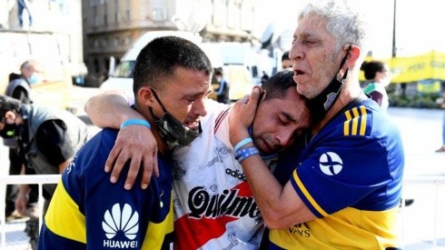 Hinchas de Boca Juniors y River Plate lloran abrazados la muerte de Maradona.