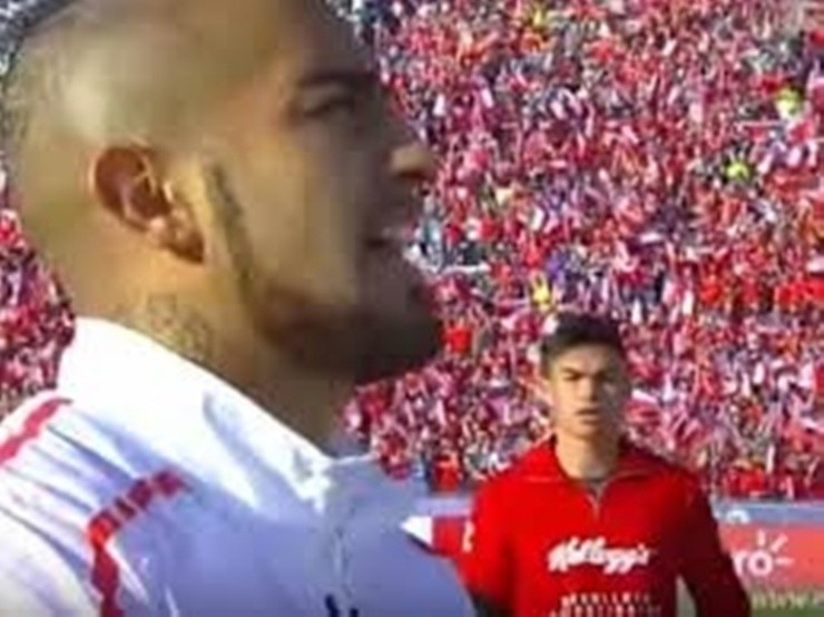 Un juvenil Gabriel Suazo mira con atención a Arturo Vidal mientras entona el himno chileno