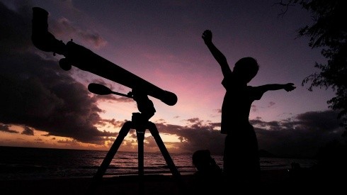 Un niño se prepara para ver el cielo con su telescopio.