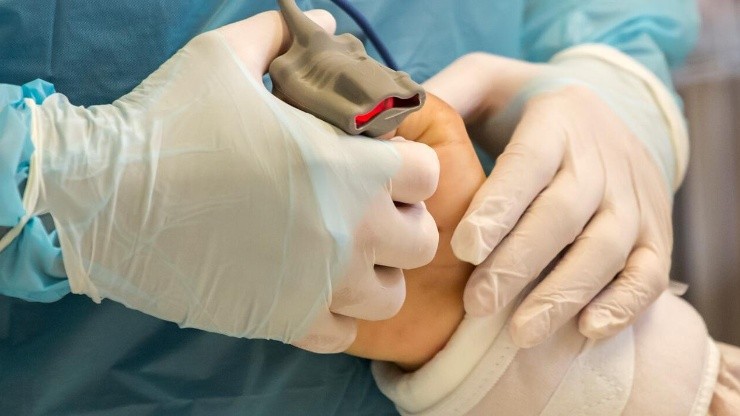 Un enfermero de la UCI del Hospital Base San José de Osorno sostiene la mano de un paciente intubado.