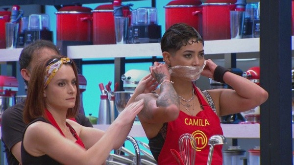 Camila Recabarren intentando ser contenida por sus compañeros de equipo en Masterchef Celebrity.