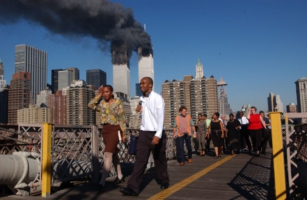 Personas caminan sobre el puente de Brooklyn mientras el World Trade Center arde | Foto: Getty Images
