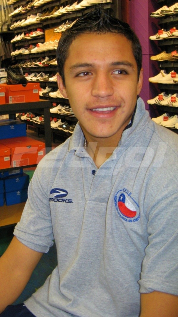 Alexis Sánchez muy sonriente en una tienda de zapatillas