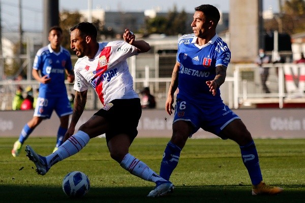Ronald de la Fuente conduce la pelota en un duelo ante Yonathan Andía en el partido entre Curicó Unido y la Universidad de Chile. (Agencia Uno).