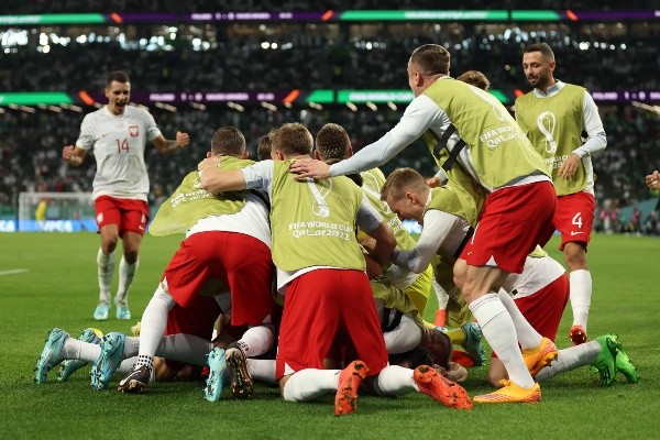 La montaña de jugadores de Polonia en la celebración del primer gol de Robert Lewandowski en un Mundial. (Getty Images 2022).