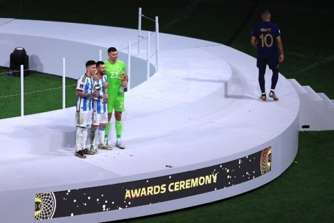 Kylian Mbappé baja del podio, mientras Lionel Messi, Enzo Fernández y Emiliano Martínez se quedan en él. (Getty Images 2022).